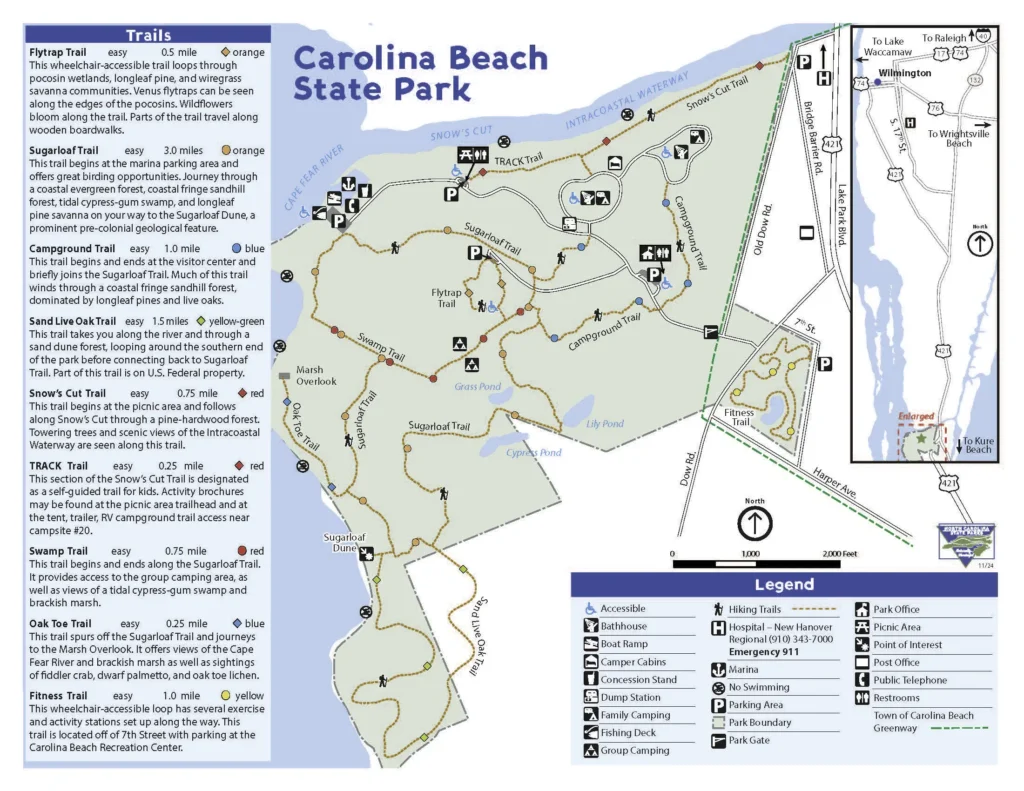 Map of Carolina Beach State Park with a left panel of trail descriptions and a central map showing trails, icons for amenities, and an inset road map at the right. It highlights Flytrap, Sugarloaf, Campground, Sand Live Oak, Snow’s Cut, and Track trails with legend and parking icons.